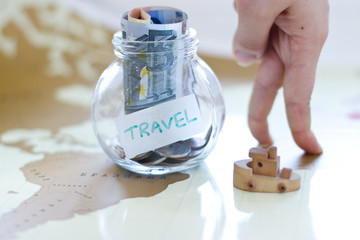 Travel budget - vacation money savings in a glass jar on world m