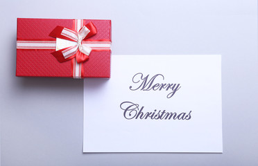 Merry Christmas text with gift boxes on white wood background, top view