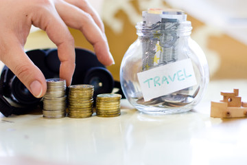 Travel budget - vacation money savings in a glass jar on world m