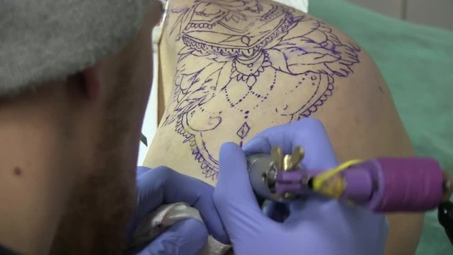 A Tattoo Artist Is Tattooing A Hip Of A Young Girl