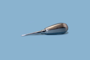 Tool of dentist for teeth removal on blue background