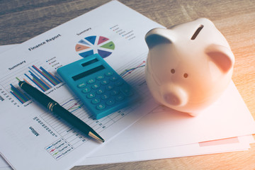 Piggy bank with calculator on wood table, business and finance concept, vintage color tone.