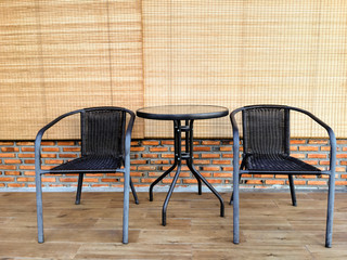 Two black chairs with round table on wood floor, brick wall and
