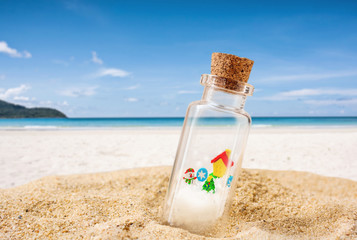 Christmas decorative in bottle on sand beach with sun ray over blurred tropical blue sea background, Image for Christmas holiday vacation travel concept