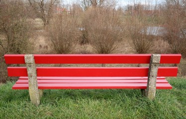 a red bench and willow trees in the background