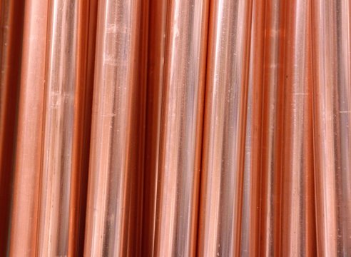 A row of copper pipes. A clear photo of a finished product, derived from a natural chemical element, copper ore. For the replacement or installation of a water pipe during the renovation of a house.