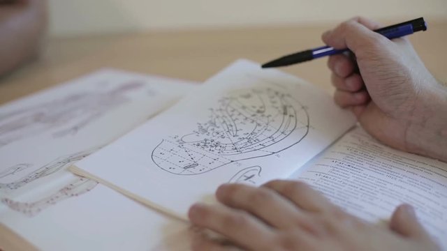 Hands of the doctor on the book with an illustration of a human ear and acupuncture points.