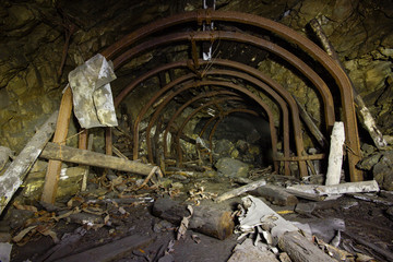 Abandoned old ore mine shaft tunnel passage with arched metal barring