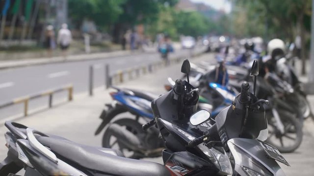 Close up of an Indonesian stop place for bikes. Indonesian mopeds are standing on parking area in Bali. Typical Balinese transport is fixed along the street.