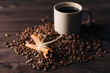 Coffee beans and cup of coffee on table on brown background