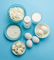 Protein products: cheese, cream, milk, eggs on the blue backgrou