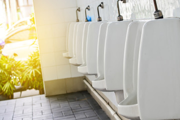 Close up white urinal in men’s bathroom in sunlight