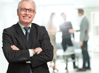 Fototapeta premium Happy mature business man looking at camera with satisfaction at office