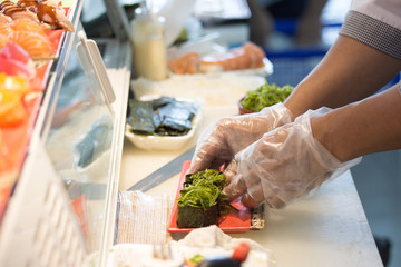 chef hand in glove cooking seaweed maki roll