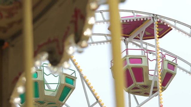 Ferris Wheel with a spinning carousel in forgeround with refocus at Christmas Fiar (1080p, 25fps, tripod)