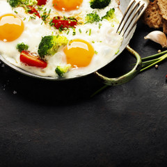 Pan of fried eggs, broccoli and cherry-tomatoes, top view