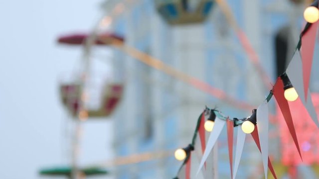 Christmas fair details with garland in front of spinning Ferris wheel (1080p, 25fps, tripod)