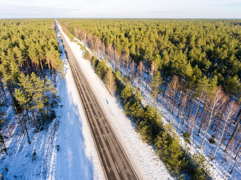 Aerial infinity road in winter surrounded by forest