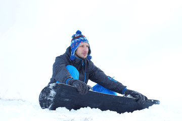 Fototapeta na wymiar Young man sitting on the snow buttoned in snowboard