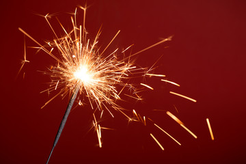 Fototapeta premium Burning sparkler on red background