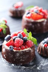Sweet chocolate cakes with berries on black wooden table