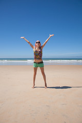 Fototapeta na wymiar woman with headscarf green shorts opening arms at a beach 