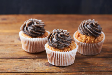 Close view at tasty chocolate cup cakes over wooden background
