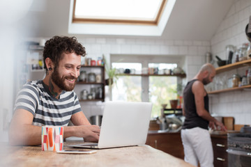 Gay couple using laptop in the kitchen
