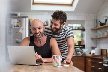 Fototapeta na wymiar Gay couple using laptop in the kitchen
