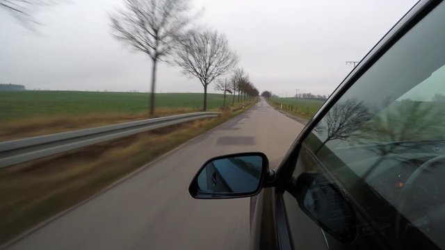Black car driving on a country road on the evening - camera outside the driver's door