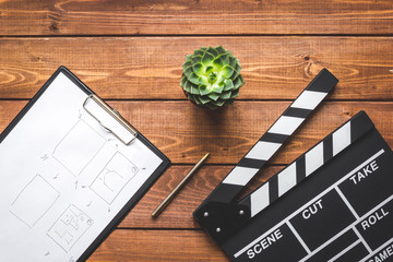 Fototapeta premium Screenwriter desktop with movie clapper board wooden background top view