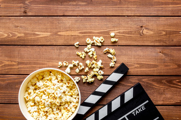 Naklejka premium watching movie with popcorn on wooden background top view