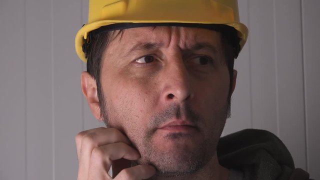 Confused construction worker with yellow hardhat resolving a project problem