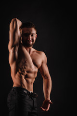 Obraz na płótnie Canvas Bodybuilder posing on a black background. Dramatic portrait of an athlete. Drying. Relief and sculptural muscles of the body. Healthy lifestyle concept. Abdominal muscles and shoulders, triceps.