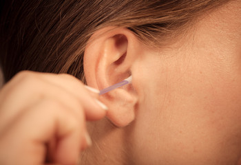 Woman cleaning ear with cotton swabs closeup