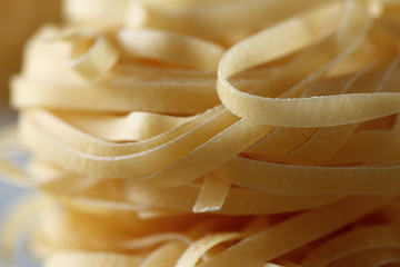 raw rolls of Italian tagliatelle noodle on a wood