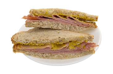 Applewood smoked ham sandwich on a plate isolated on a white background.