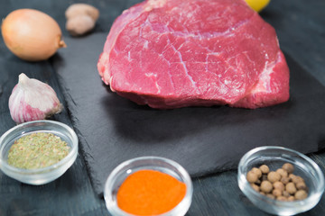 Raw beef steak on a cutting board with spices.