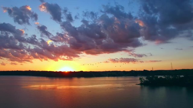 Amazing sunrise over vast river with geese, drone aerial view.
