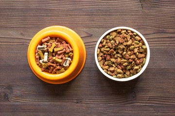 dry dog food in bowl on wooden background top view