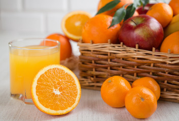Fresh orange juice in a glass on a background of fruit baskets