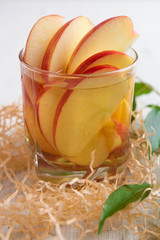 Fresh apple juice in a glass with slices of apples closeup
