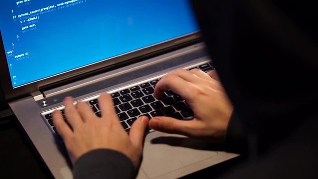 The Hacker in a Hood with Notebook Cracks a Computer Code