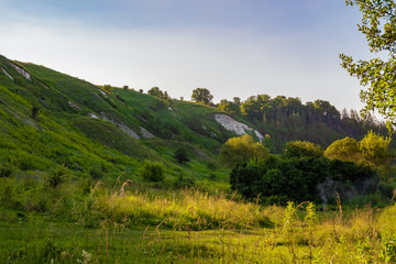 Fototapeta premium Green chalk hills under a cloudy sky. The multilayered archaeological monument - Krapivinskaya settlement, Belgorod region, Russia.