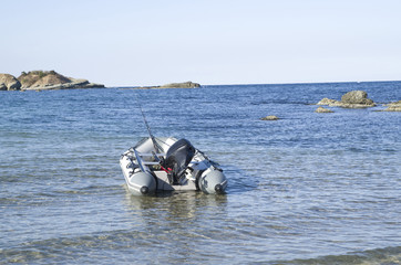 Motor rubber inflatable boat with fishing tackles in bay