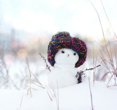 Small snowman in a knitted cap on snow in the winter. Festive background with a lovely snowman. Christmas Card copyspace
