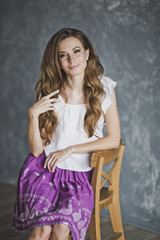 Fototapeta premium A slender girl in a purple skirt sitting on a chair 6909.