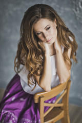 Fototapeta premium Dreaming girl with long hair sitting on a chair 6917.