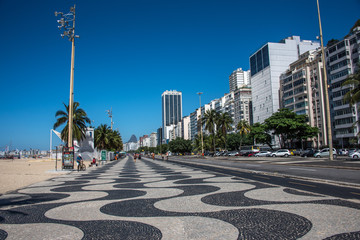 Worldwide famous Copacabana promenade with palm trees, residential buildings, hotels and black and white mosaic of Portuguese pavement in Rio de Janeiro, Brazil
