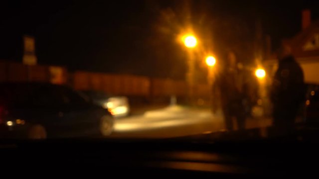 Night industrial zone, railway station full of trains. Shot from a car. Smoothed peoples, cars and railway carriage